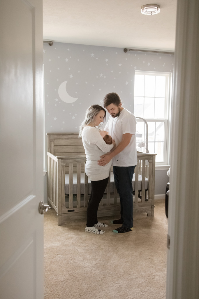 peeking in on mom and dad with newborn son in nursery