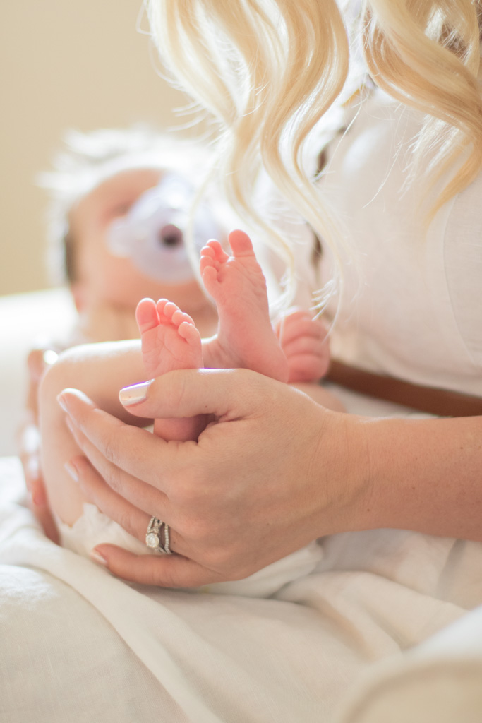 mother holding newborn son's tiny feet in her hands