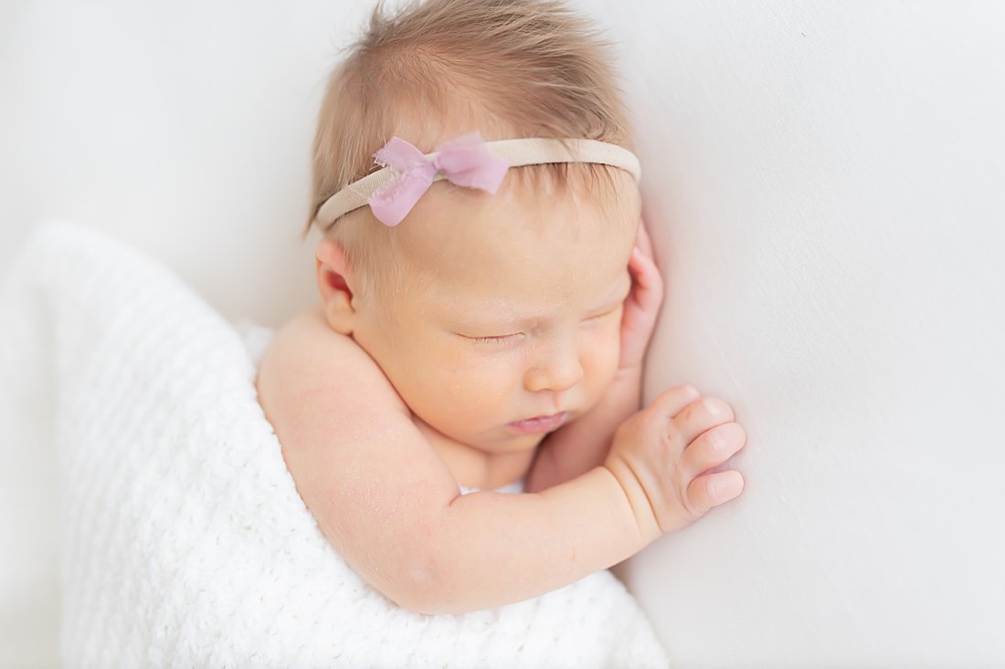 newborn baby girl tucked under white blanket in pittsburgh
