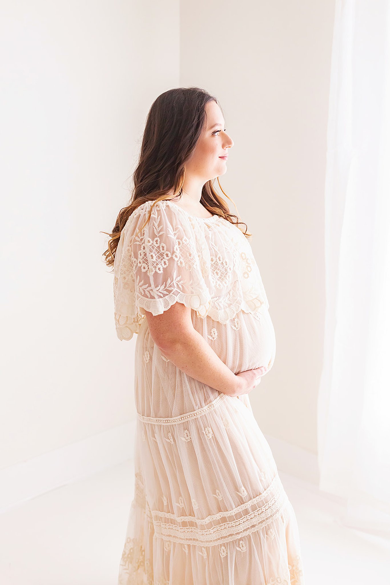 mom to be in a studio holds her bump in white gown pittsburgh doulas