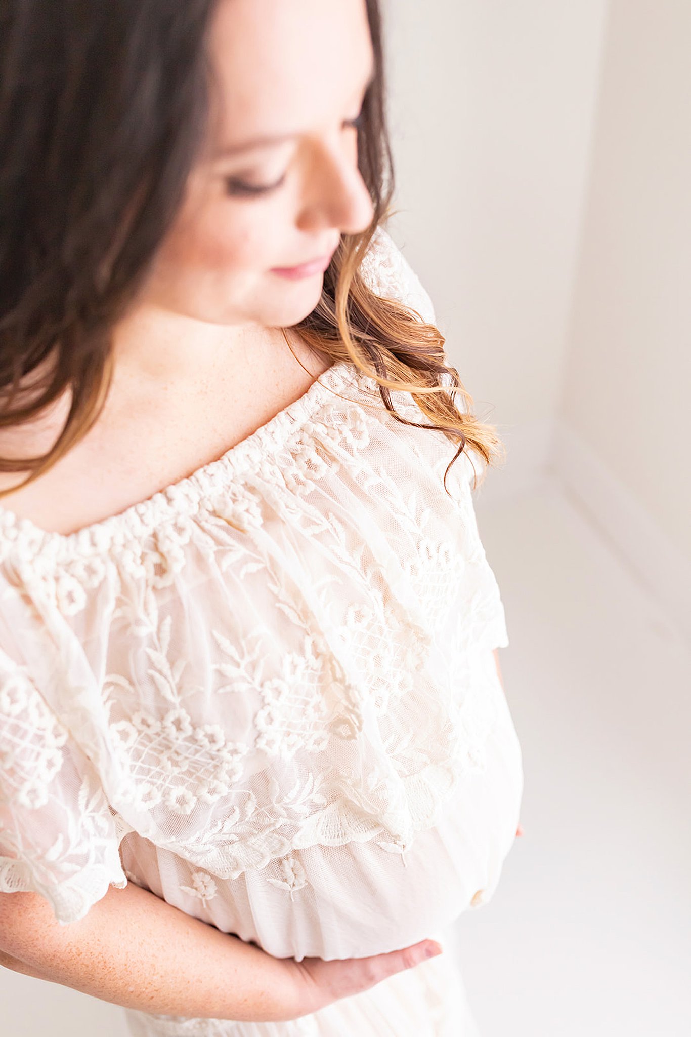 Mother to be wearing white maternity gown holds bottom of her bump pittsburgh doulas