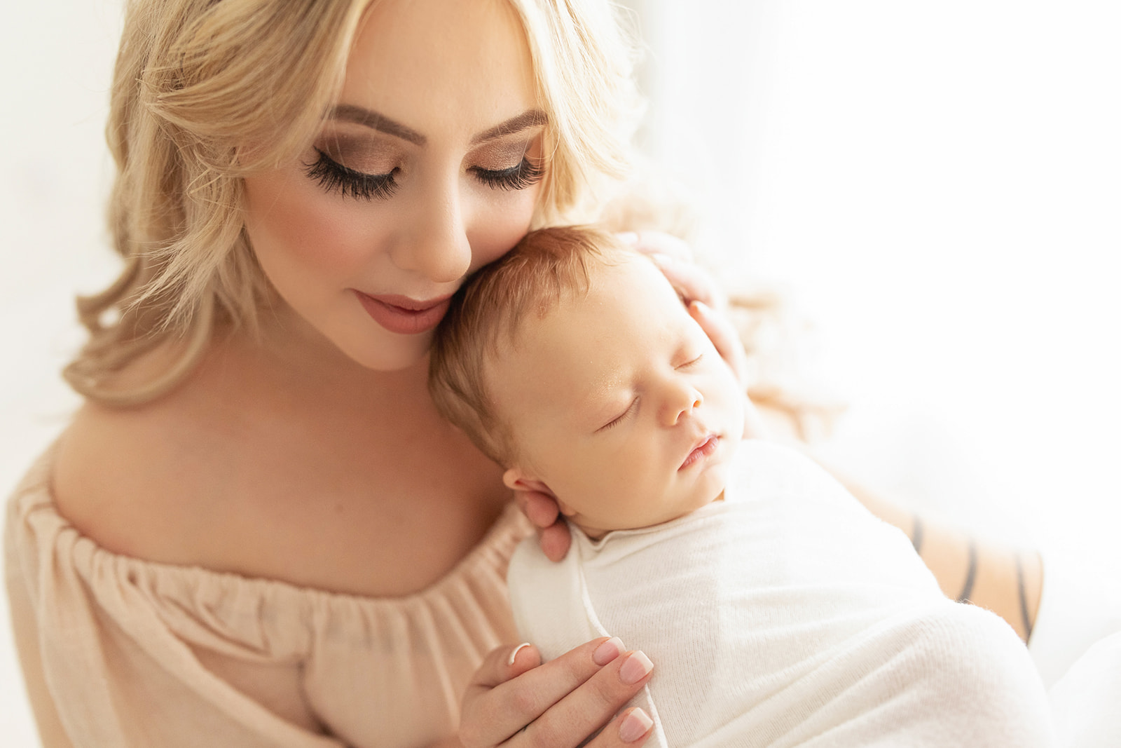 Mother to be presses her cheek against her newborn's head while it sleeps