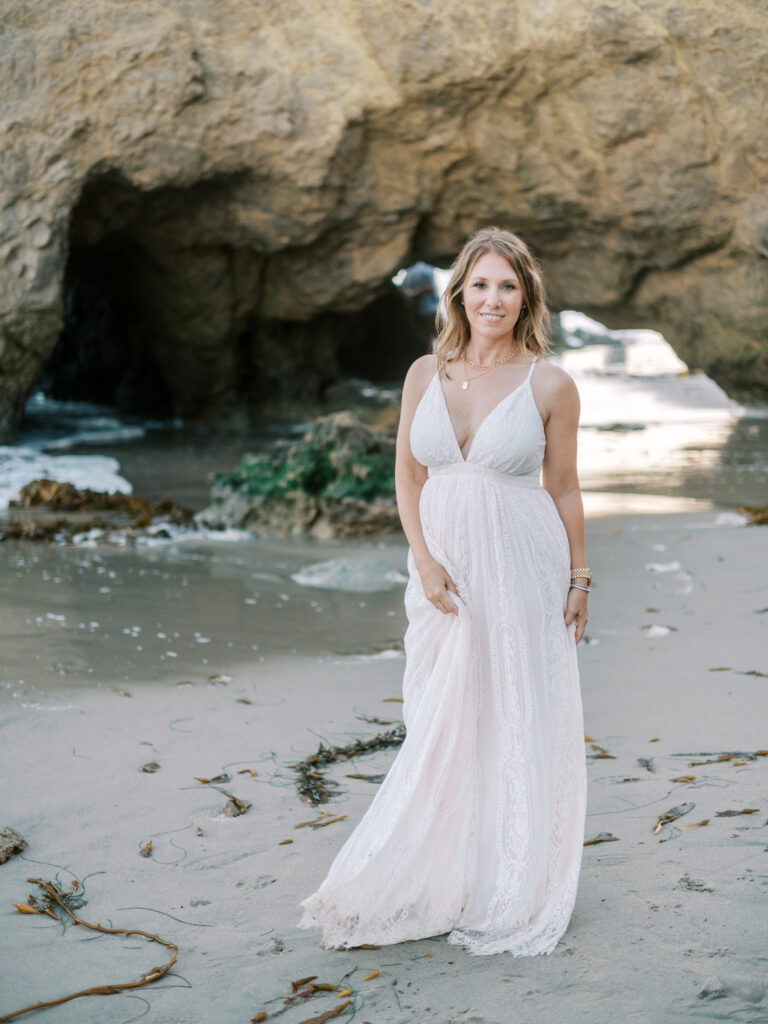 woman in long lace dress standing on malibu beach