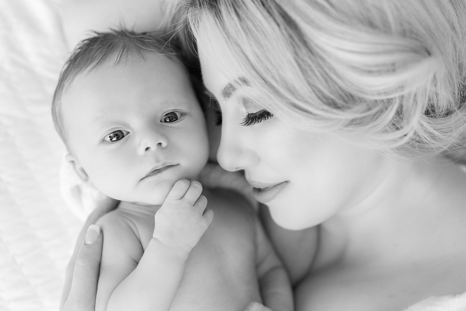 A mother snuggles with her newborn baby on a bed with eyes open Peek-A-View Baby