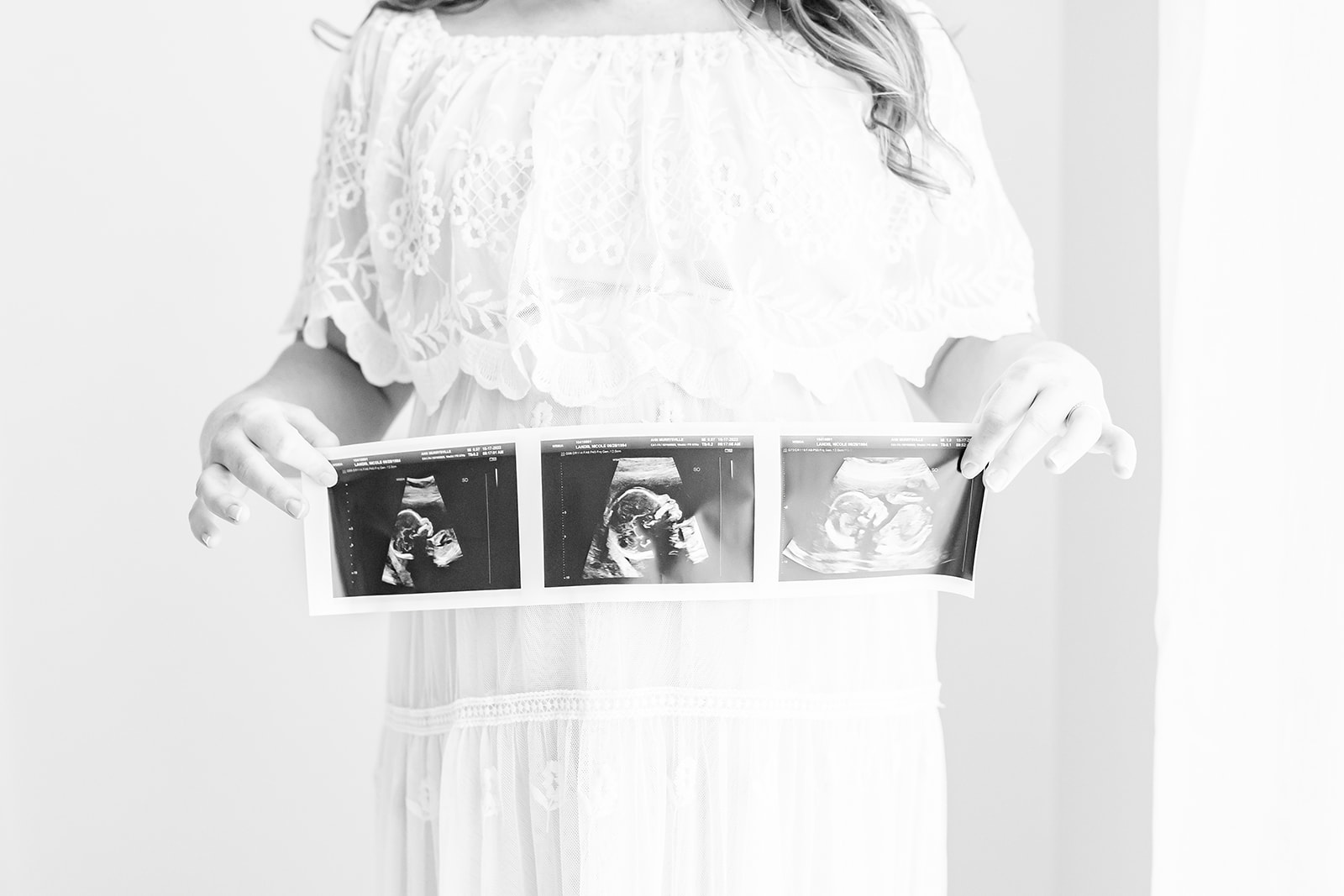 A mother to be stands in a white dress holding her sonogram in front of her bump Jefferson hospital labor and delivery