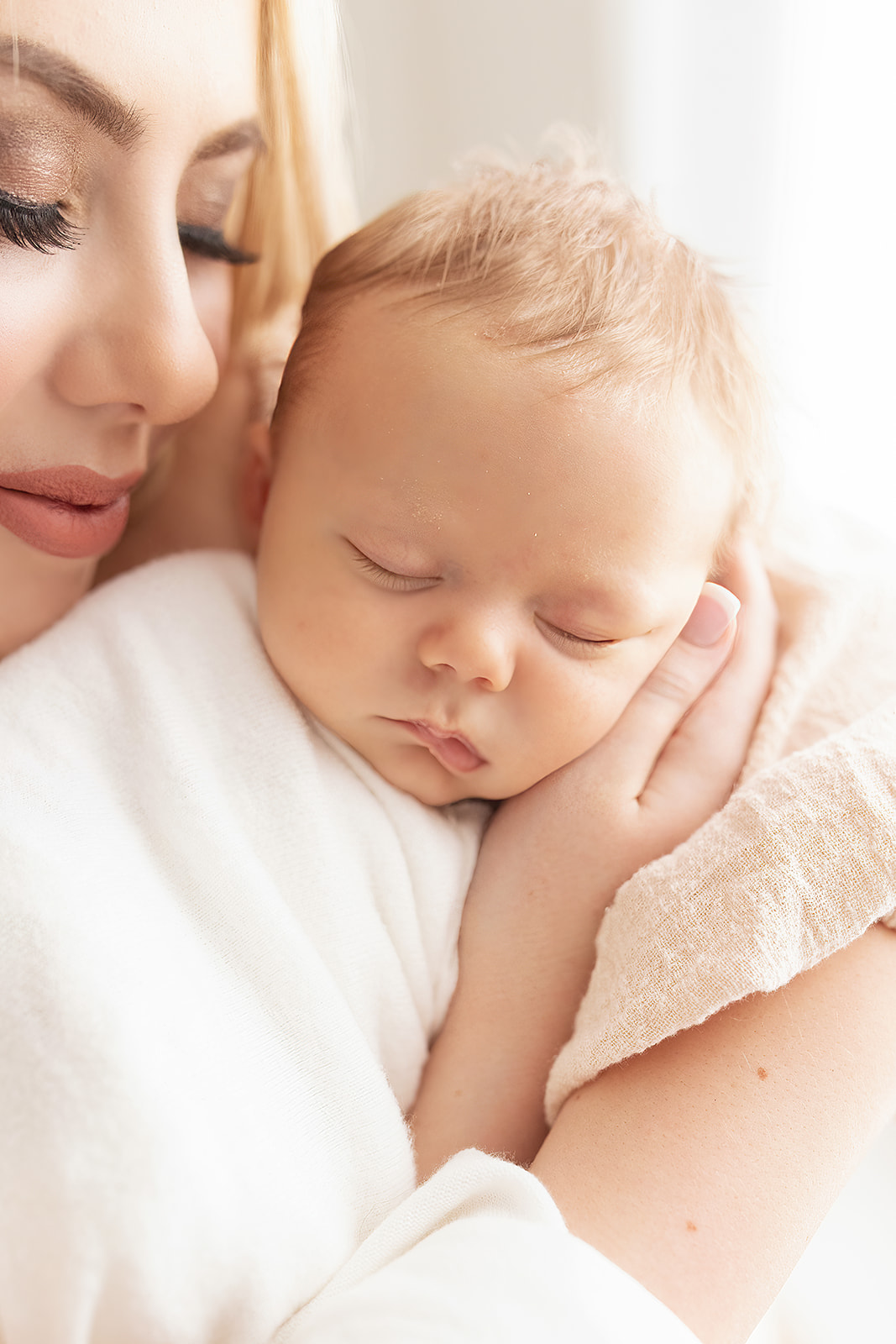 A mother cradles a newborn baby while it sleeps in her arms mom and nanny