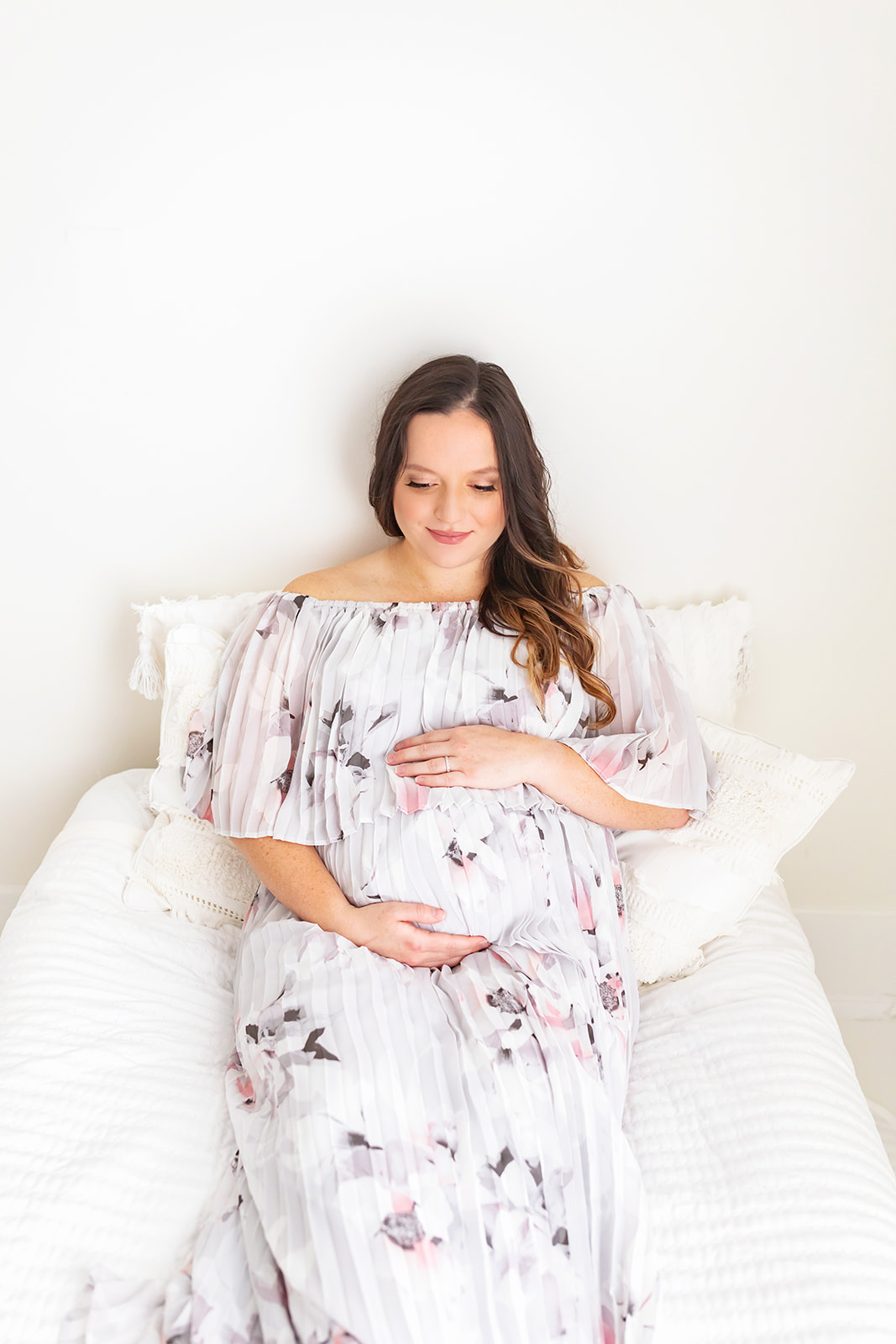 A mom to be sits on a bed while looking down at her bump Pittsburgh baby shower venues