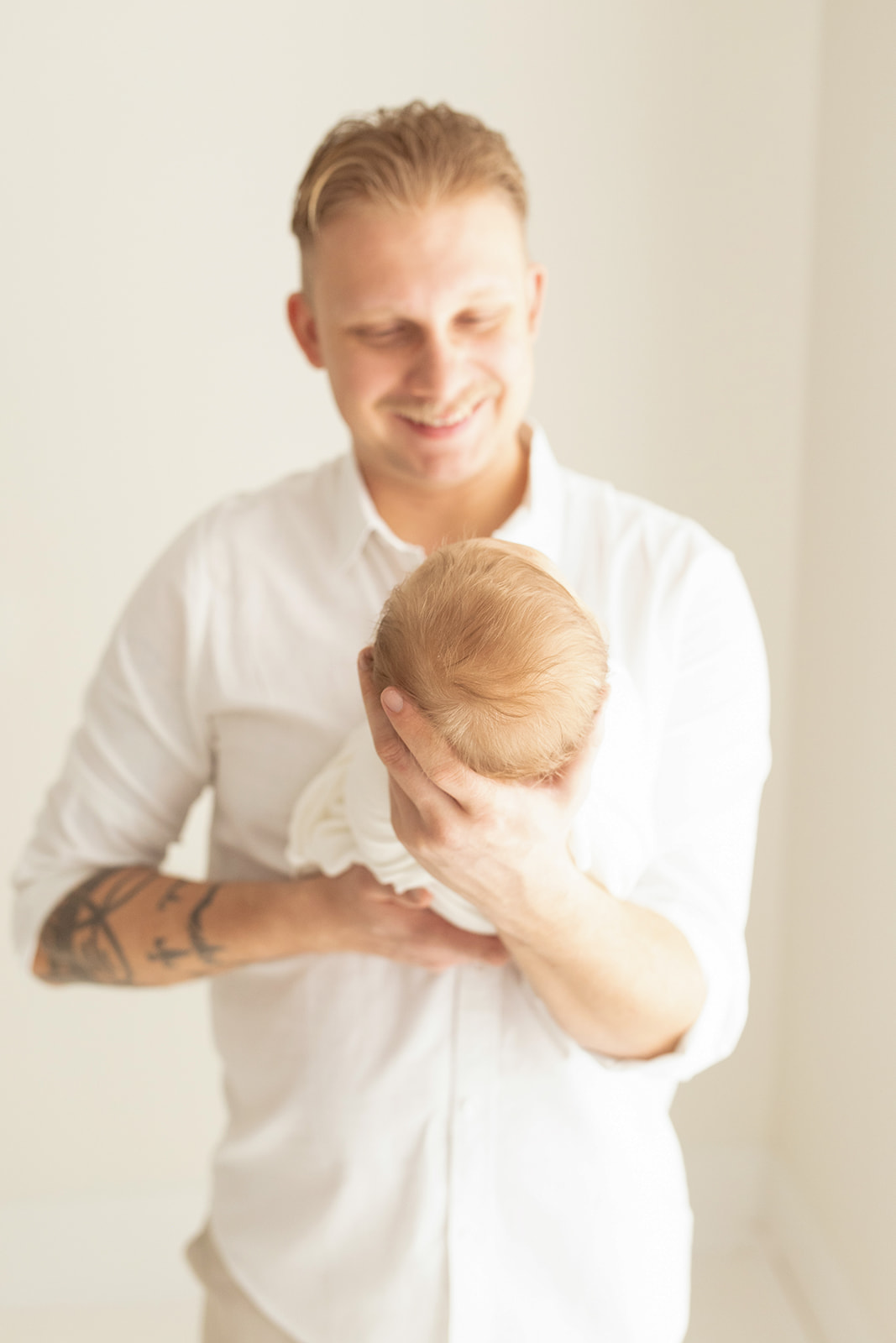 Details of a newborn baby's head while dad smiles down at it in his hands