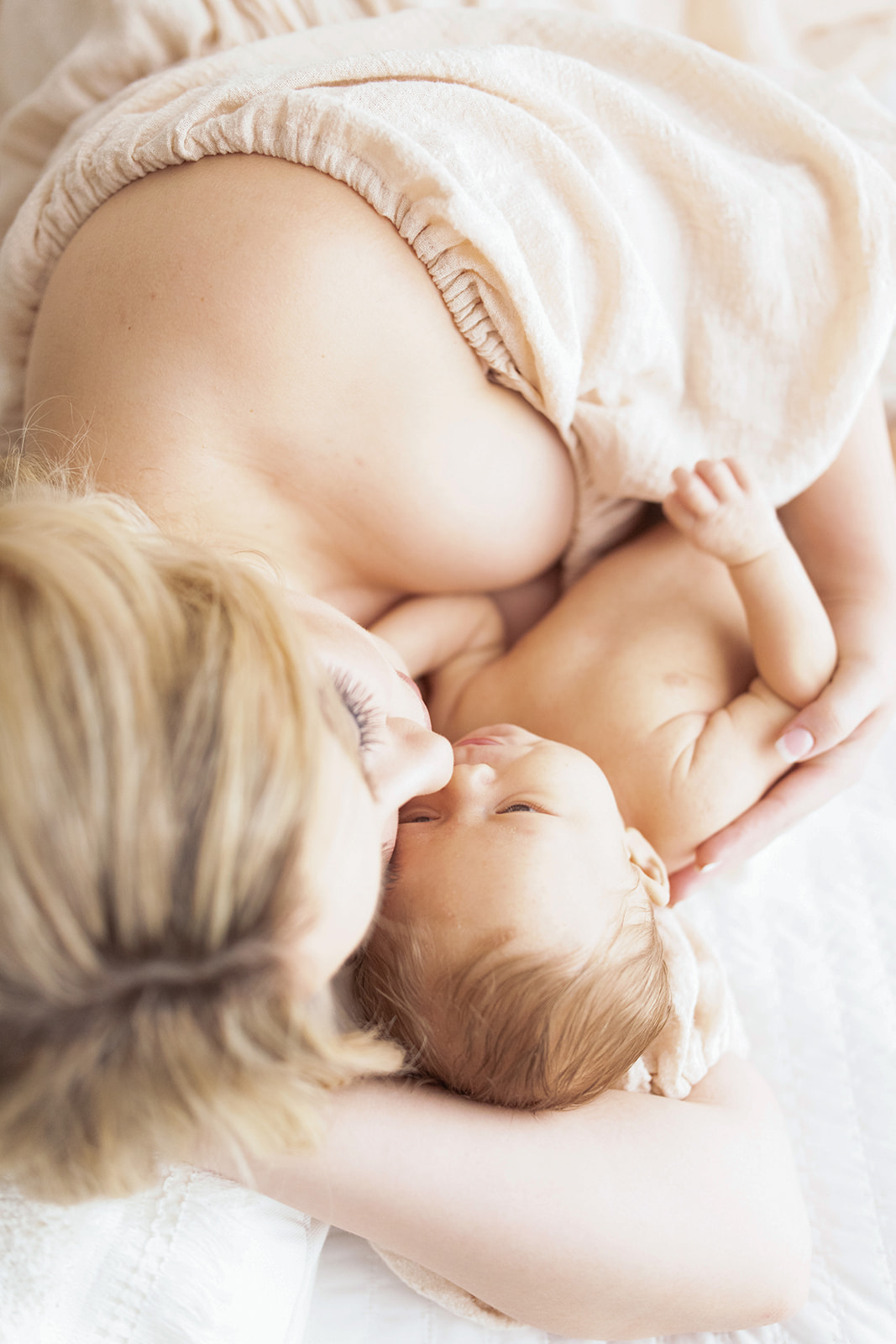 A new mom cuddles with her newborn baby on a bed