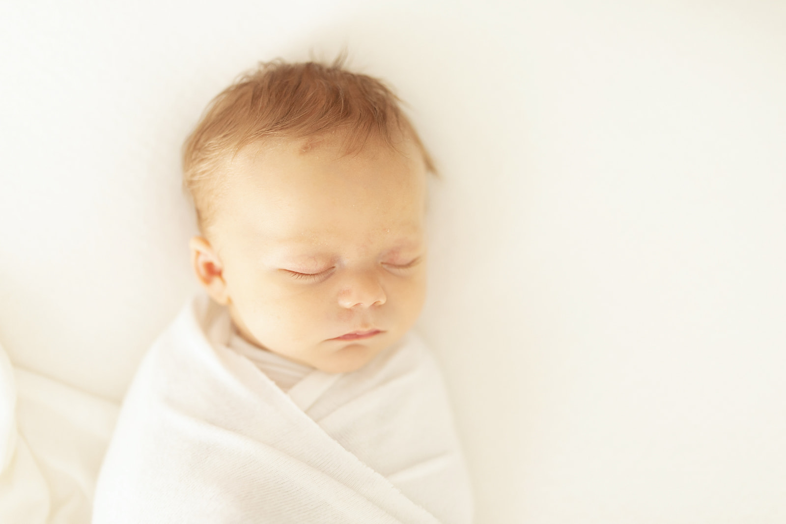 Details of a newborn baby sleeping on a white bed