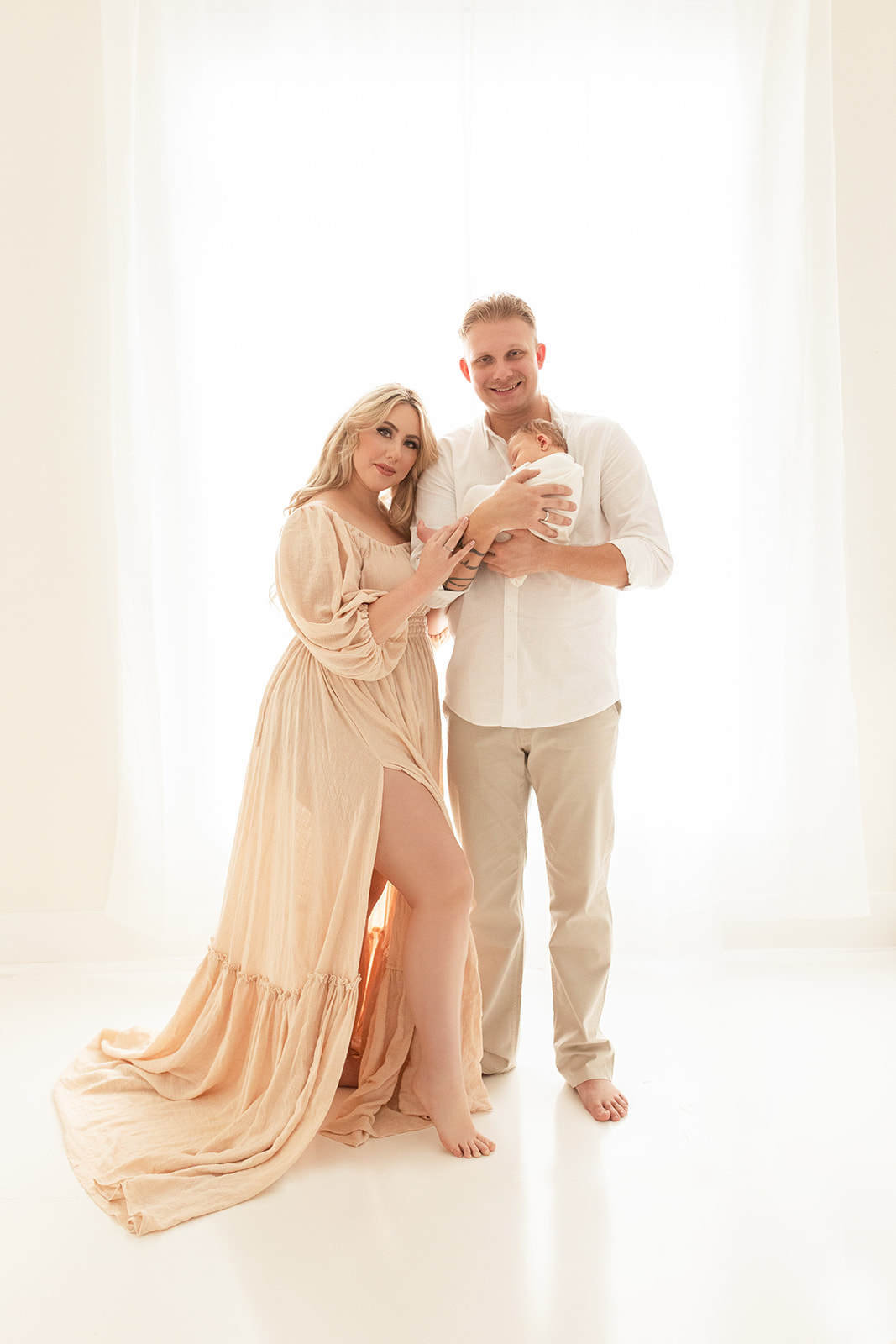 New parents stand in a studio cradling their newborn baby on dad's chest Placenta Encapsulation Pittsburgh