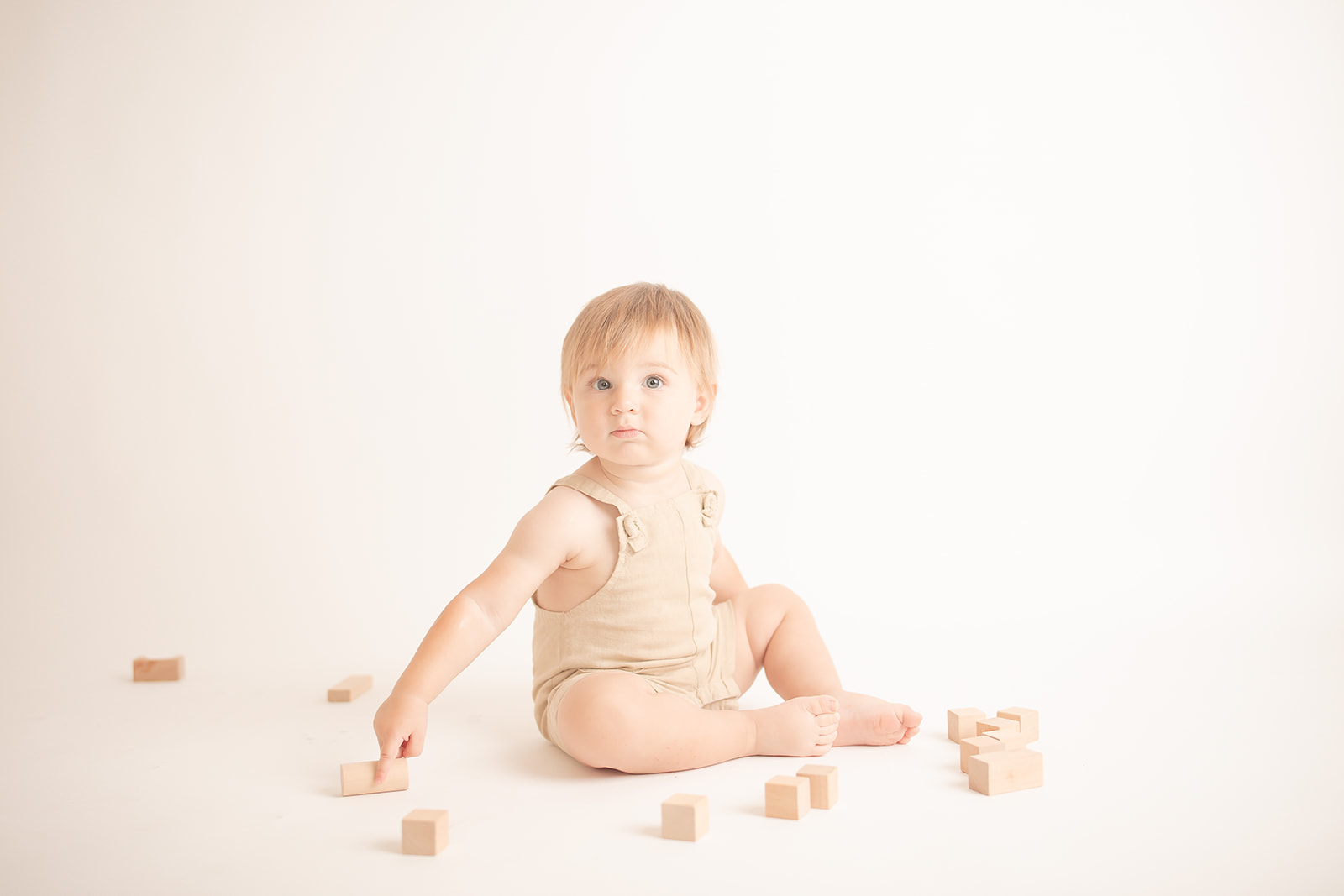 A toddler boy sits in a studio playing with wooden blocks before visiting Pittsburgh Pediatric Dentistry
