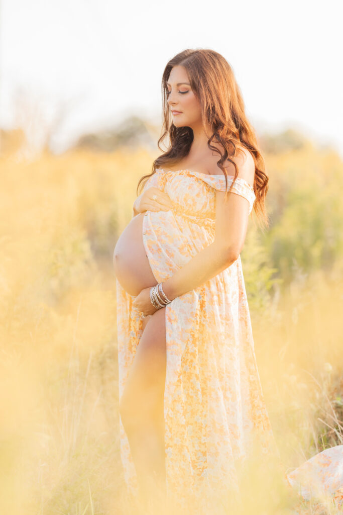 expectant mom standing in field of yellow flowers at sunset photographed by pittsburgh maternity photographer petite magnolia photography