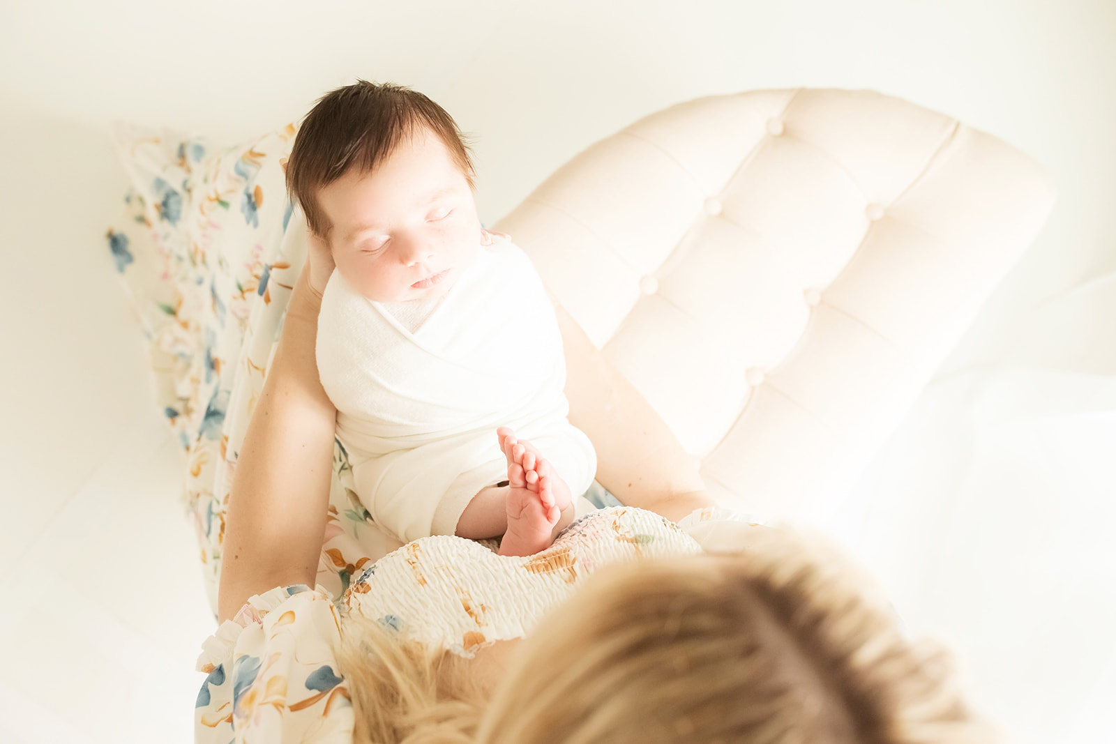 A mother holds her sleeping newborn baby in her lap in front of her for some Pittsburgh Newborn Photos