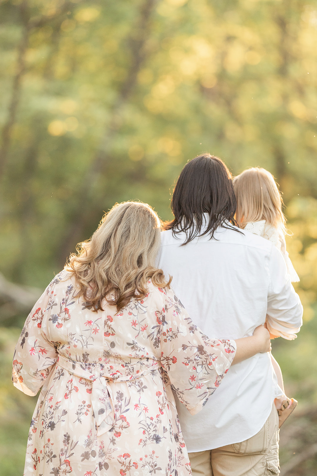 Mom and dad stand together in a forest at sunset with their toddler in dad's arms before visiting Family-Friendly Restaurants Pittsburgh