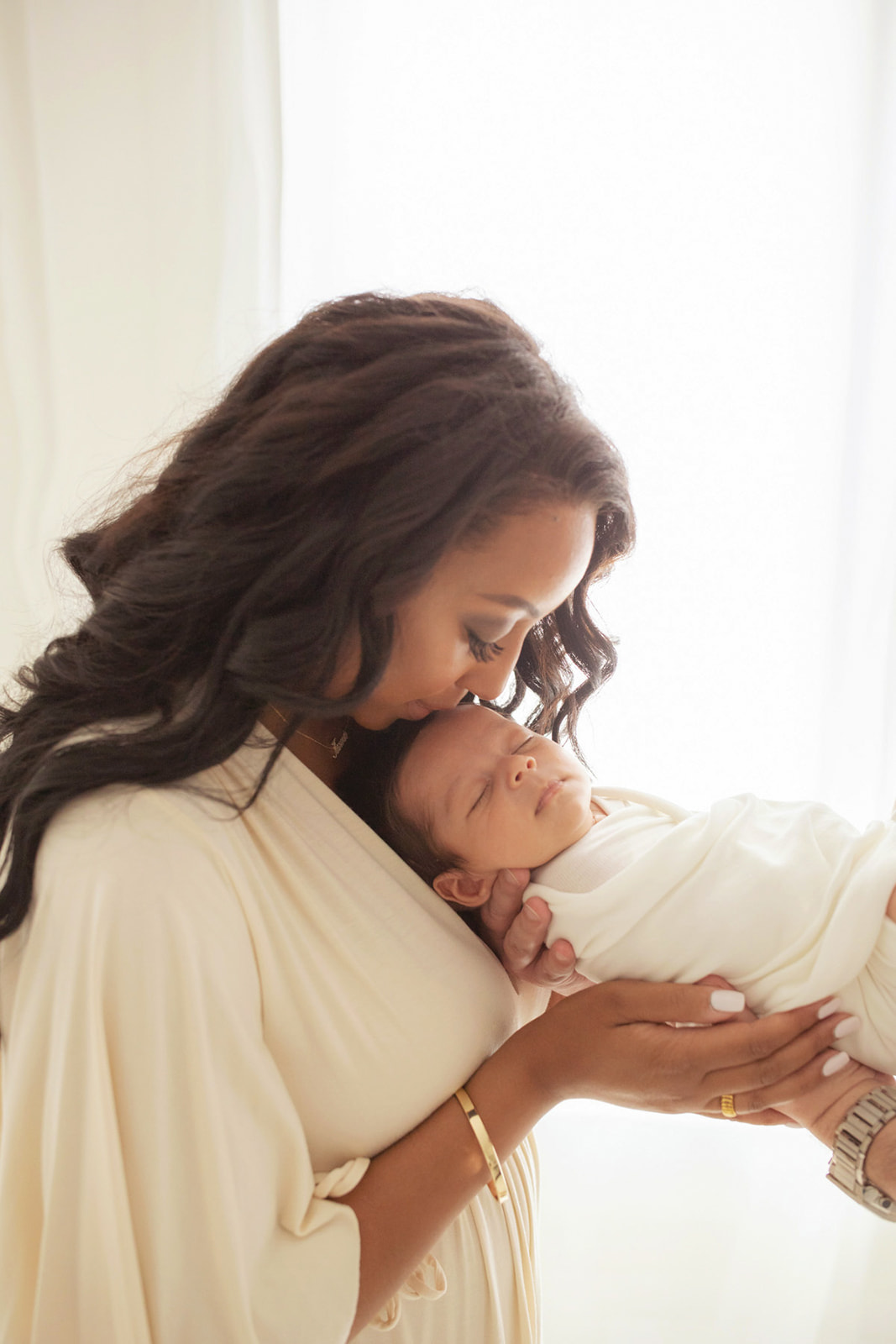 A new mom kisses the head of her sleeping newborn baby in a window after meeting with Lactation Consultants Pittsburgh