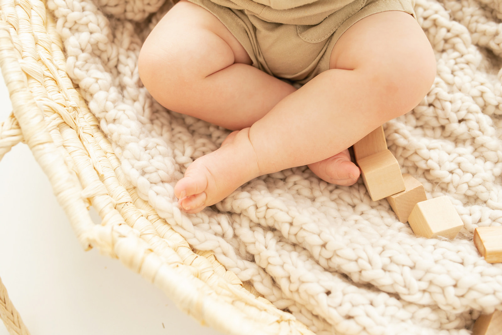 Details of a toddler boys legs while sitting in a woven basket