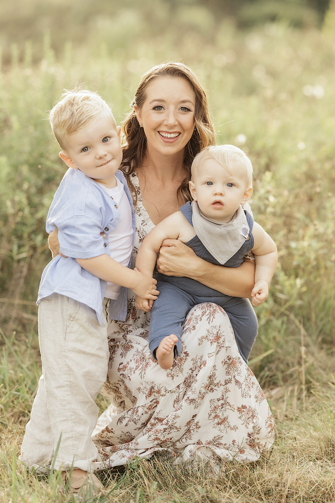 A happy mom plays with her two toddler sons in a park field at sunset before some Pittsburgh Swimming Lessons