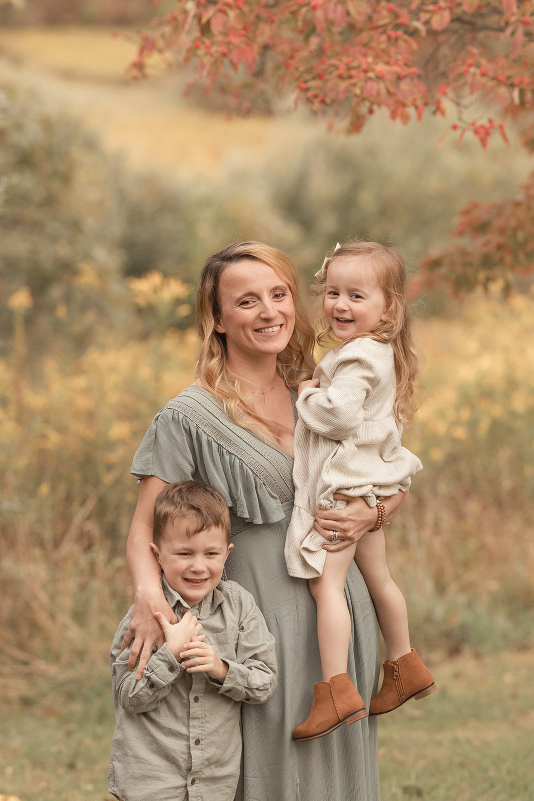 A happy mom smiles with her giggling toddler son and daughter while standing in a park before visiting private schools Pittsburgh