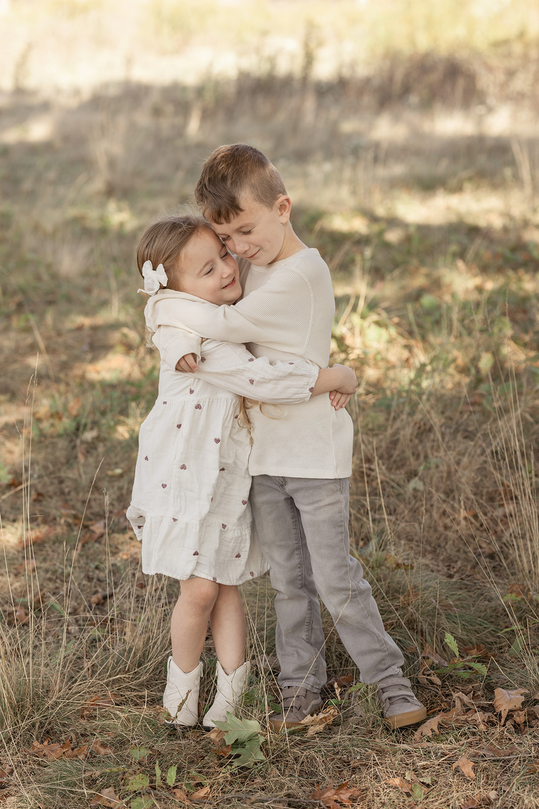 Toddler brother and sister hug in the shade in a field of tall grass before finding holiday events in Pittsburgh